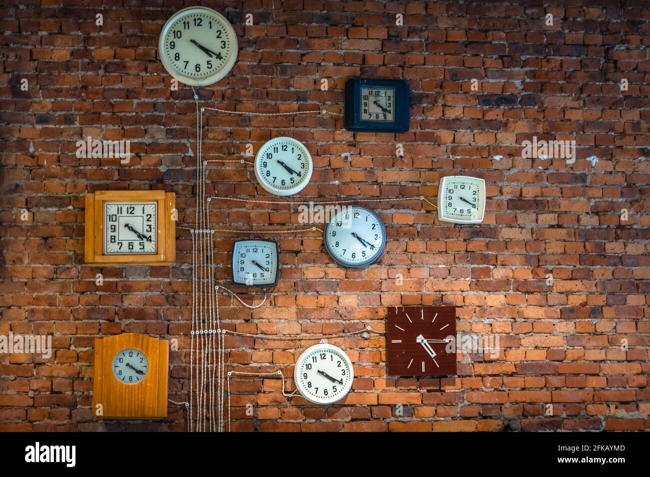 Parete di mattoni rossi decorata con antichi orologi che rappresentano precisione e. precisione Foto Stock