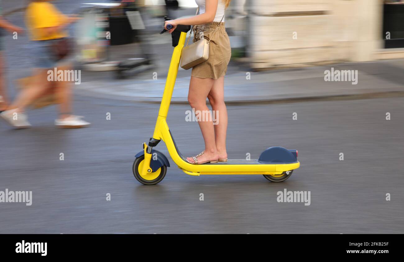 giovane donna con veloce scooter giallo corre per la città strade Foto Stock