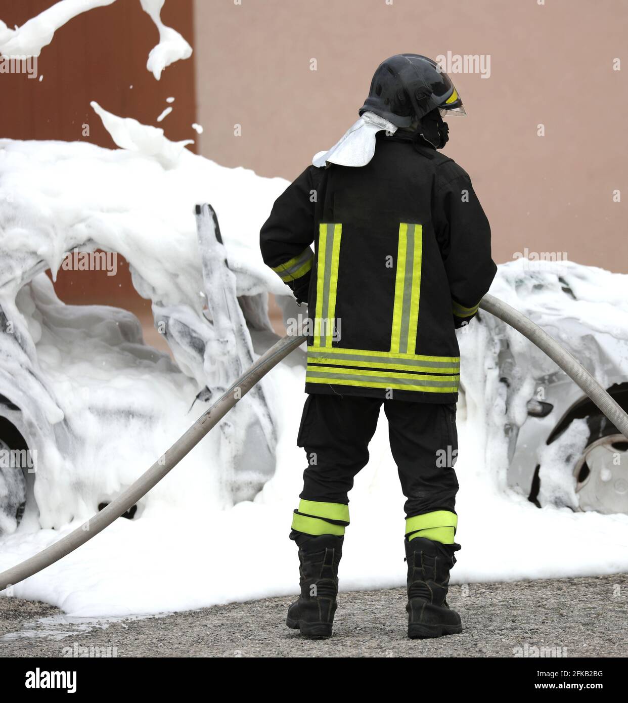 pompiere spegnere un fuoco una macchina con la schiuma dopo l'incidente dell'auto Foto Stock