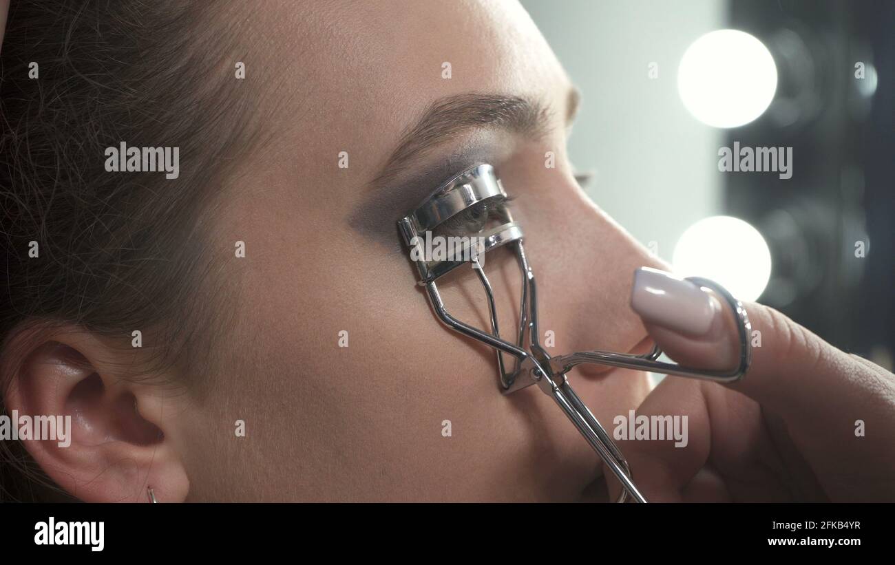 Foto del visagista che usa l'arricciatore del ciglia sugli occhi Foto Stock