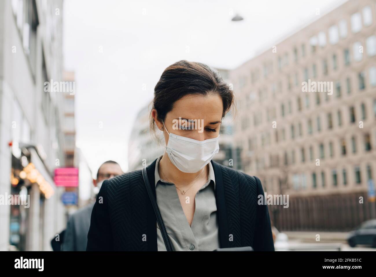 Donna imprenditore con maschera protettiva in città Foto Stock