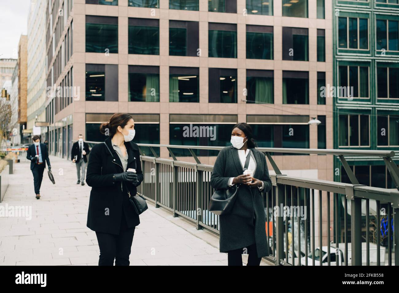 Le donne che parlano tra loro mentre camminano sul ponte in città Foto Stock