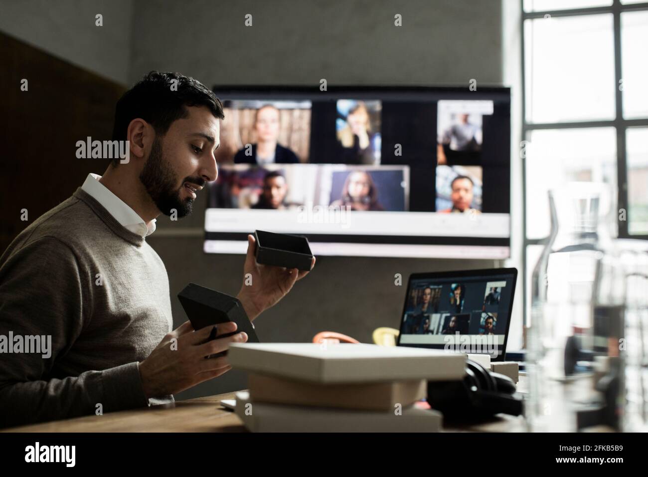 Imprenditore maschile che spiega il prodotto ai clienti attraverso una videoconferenza su un computer portatile in ufficio Foto Stock