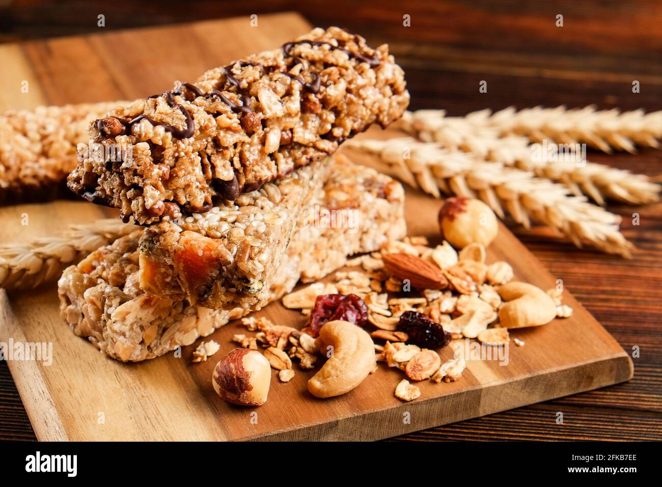 Mazzetto di barrette energetiche a base di muesli senza glutine con frutta secca e vari tipi di noci, fondo in legno. Cibo vegan sano super, diversa dieta fitness sn Foto Stock