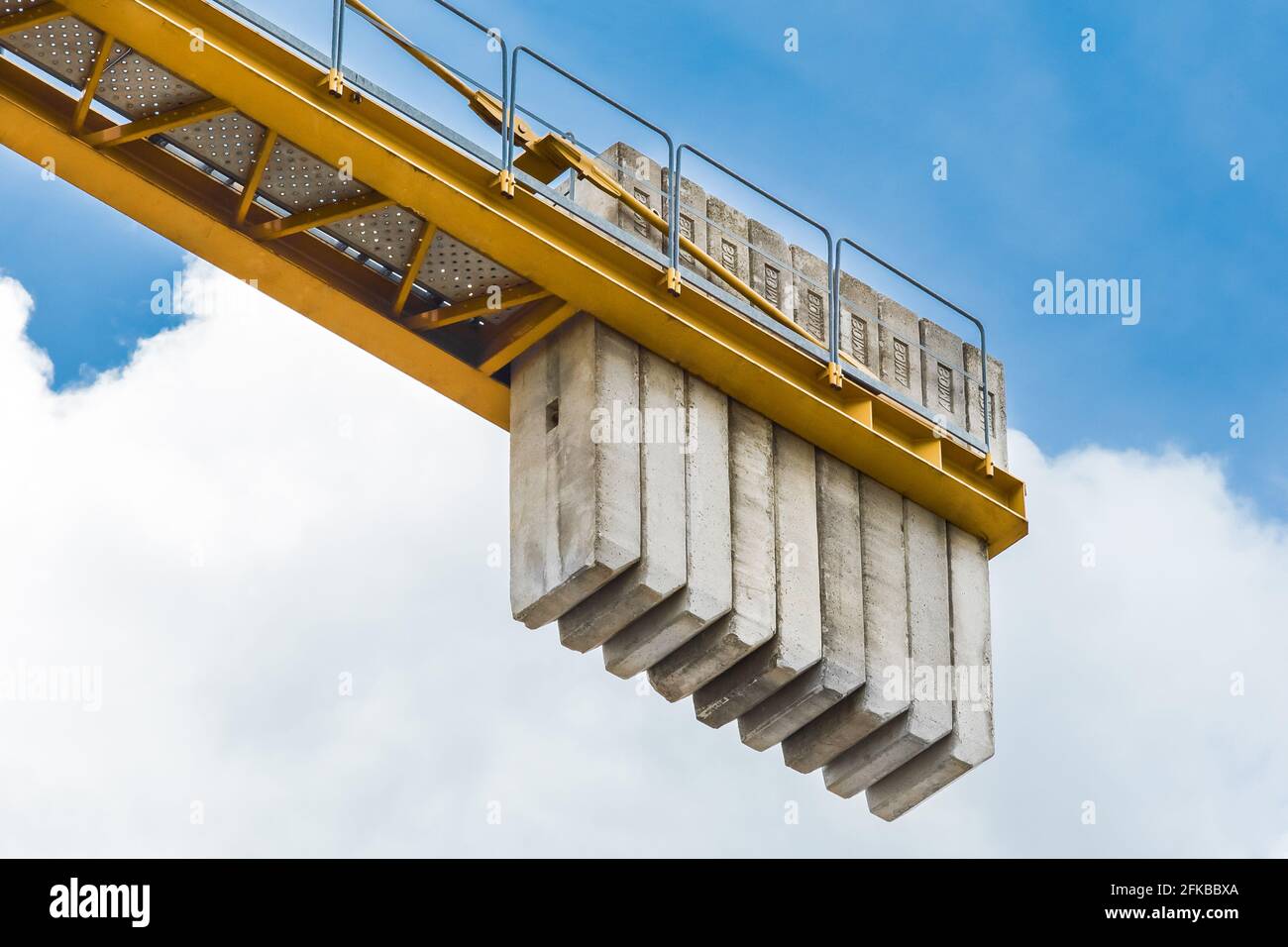Bielorussia, Minsk - 28 maggio 2020: Un contrappeso di blocchi di cemento sulla coda di una gru industriale di costruzione torre contro un cielo blu. Primo piano. Foto Stock