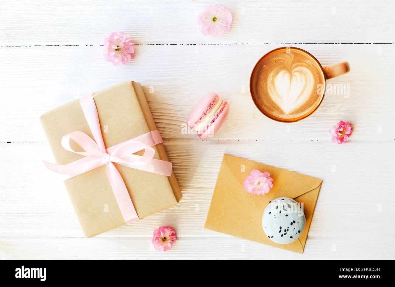 Torte del deserto di macaron francesi al gusto di mirtillo e fragola, cappuccino bruno, latte a forma di cuore, carta artigianale avvolta tulipano presente f Foto Stock