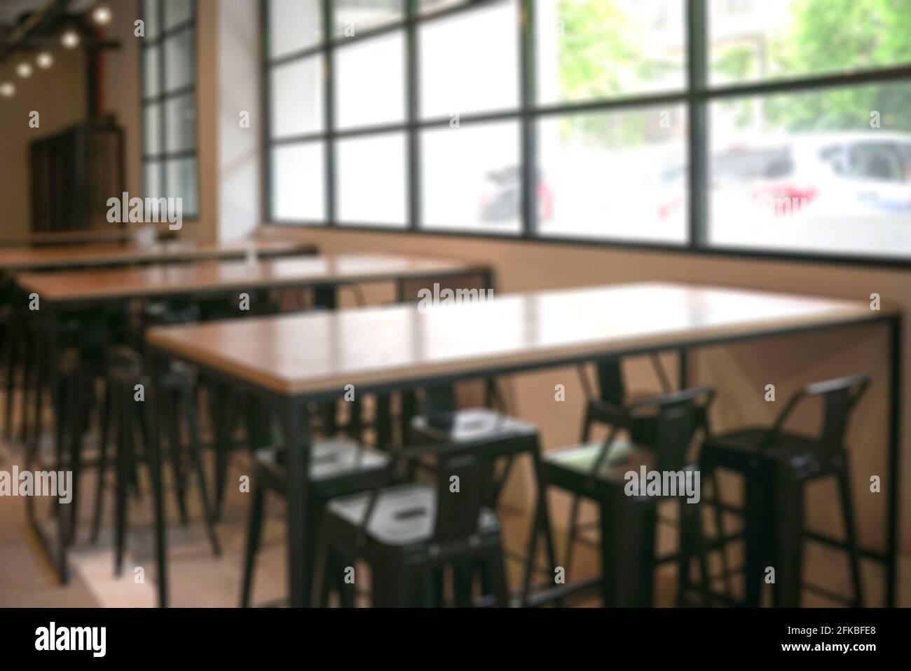 Caffetteria vuota con tavoli in legno e alte sedie e finestre con vista esterna. Sfocato. Foto Stock