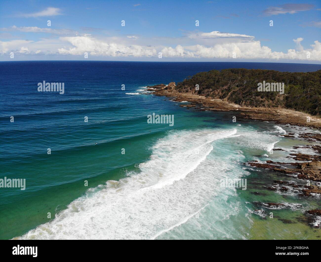 Cielo blu, nuvole bianche e spiaggia di sabbia marrone, Berial colpo del mare a Cuttagee, NSW, Australia. Foto Stock