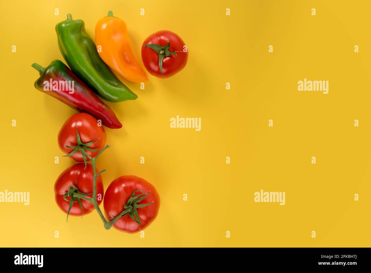 pomodori e peperoni disposti come cornice su sfondo giallo con spazio di copia Foto Stock