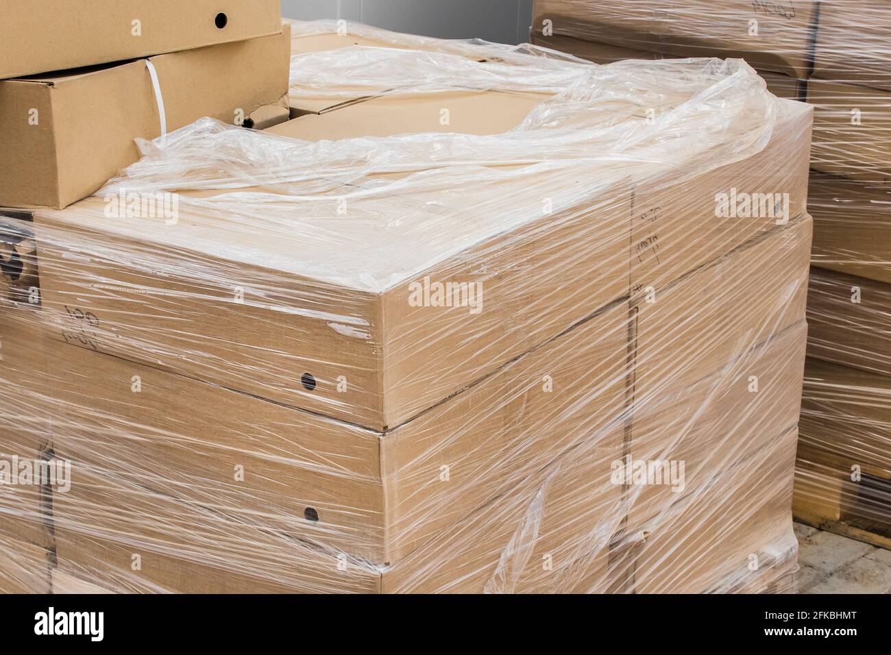 Un mazzetto di scatole di cartone con materiali da costruzione imballati in involucro di plastica nel cantiere. Foto Stock