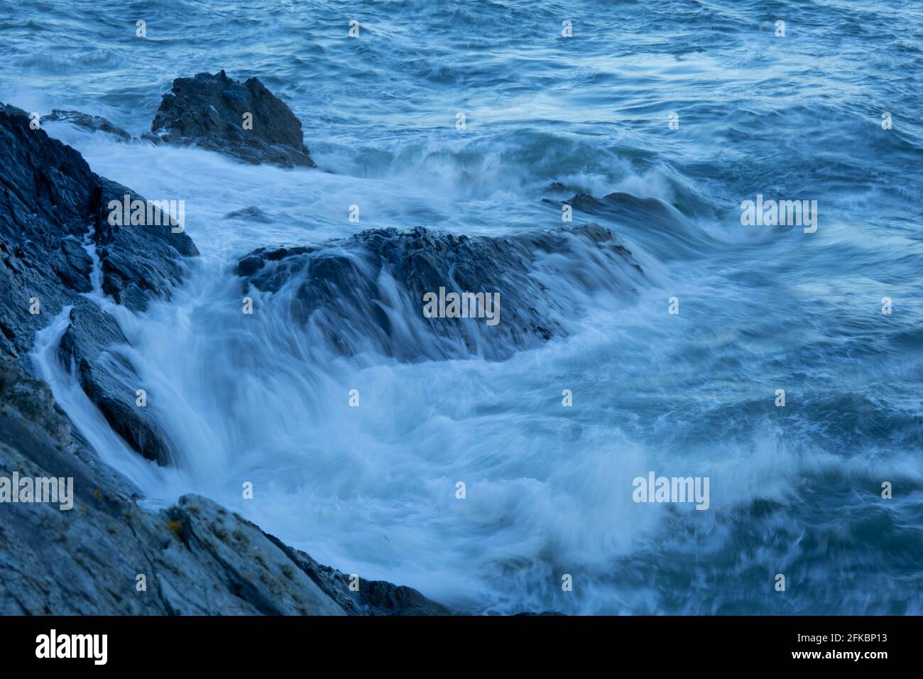 Onde che si schiantano contro le rocce su Anglesey, sentiero costiero gallese. Foto Stock