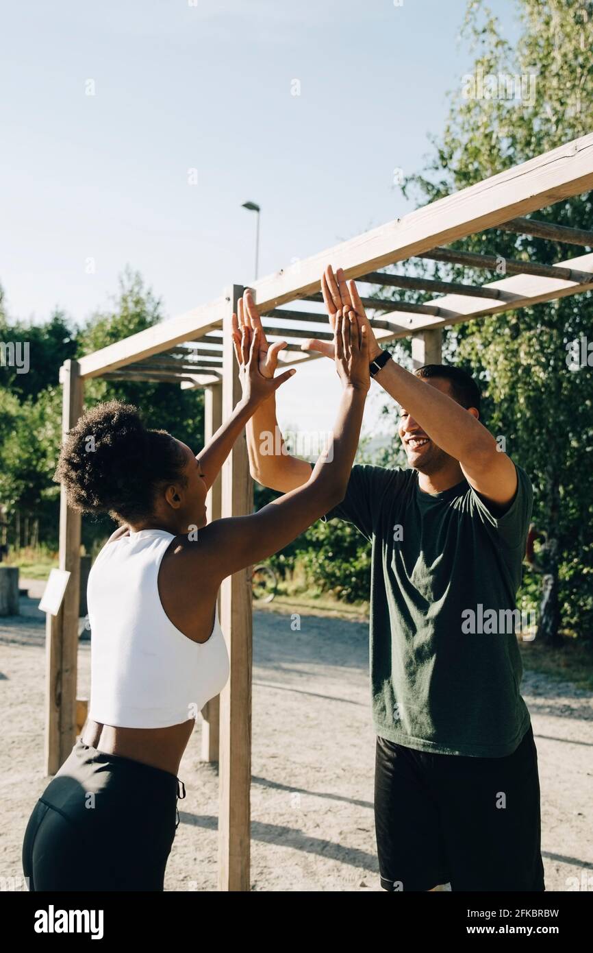 Atleta maschile e femminile che dà high-five al parco Foto Stock