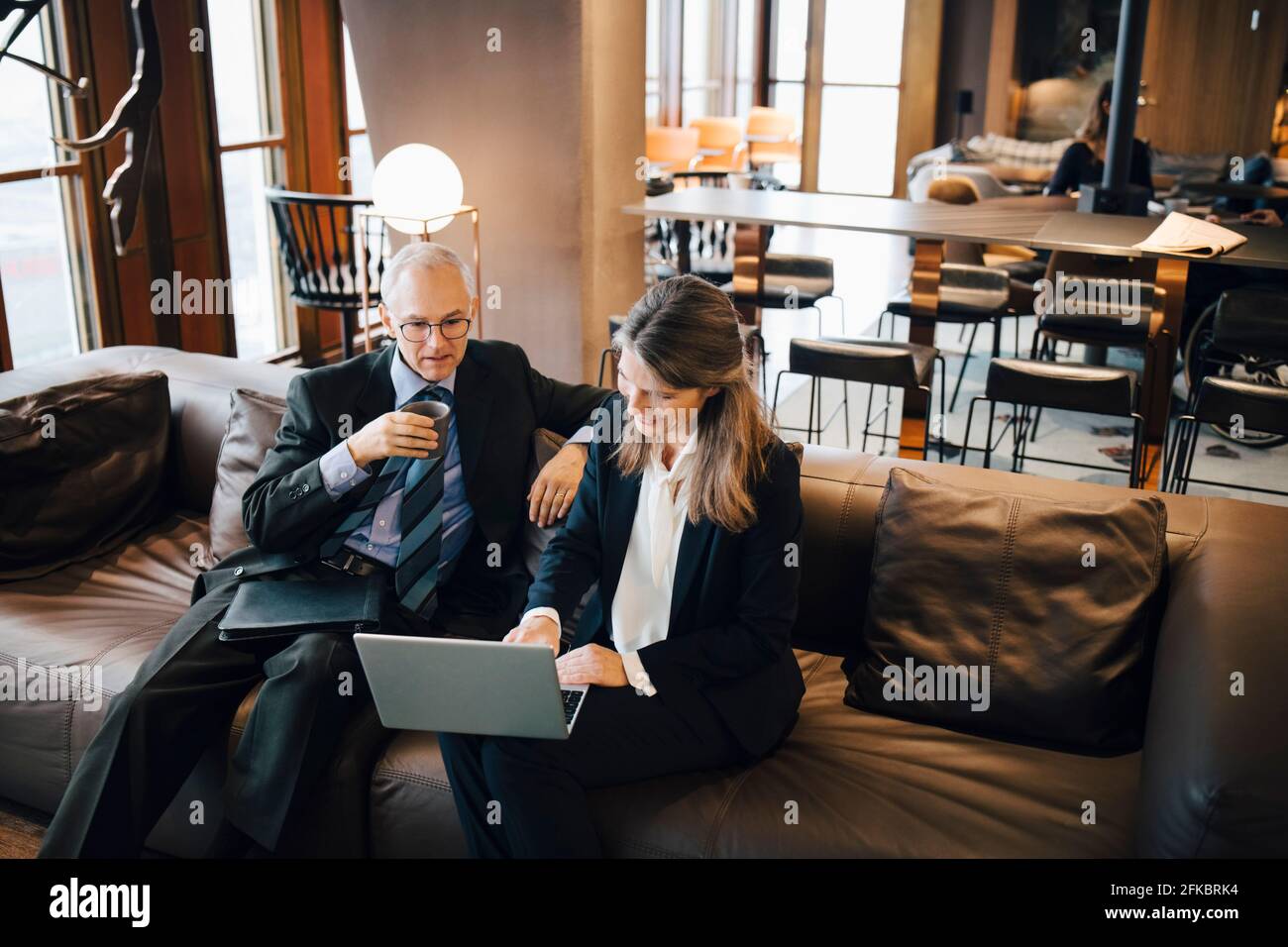 Imprenditore maschile e femminile che discute su computer portatile mentre si ha il caffè in caffetteria Foto Stock