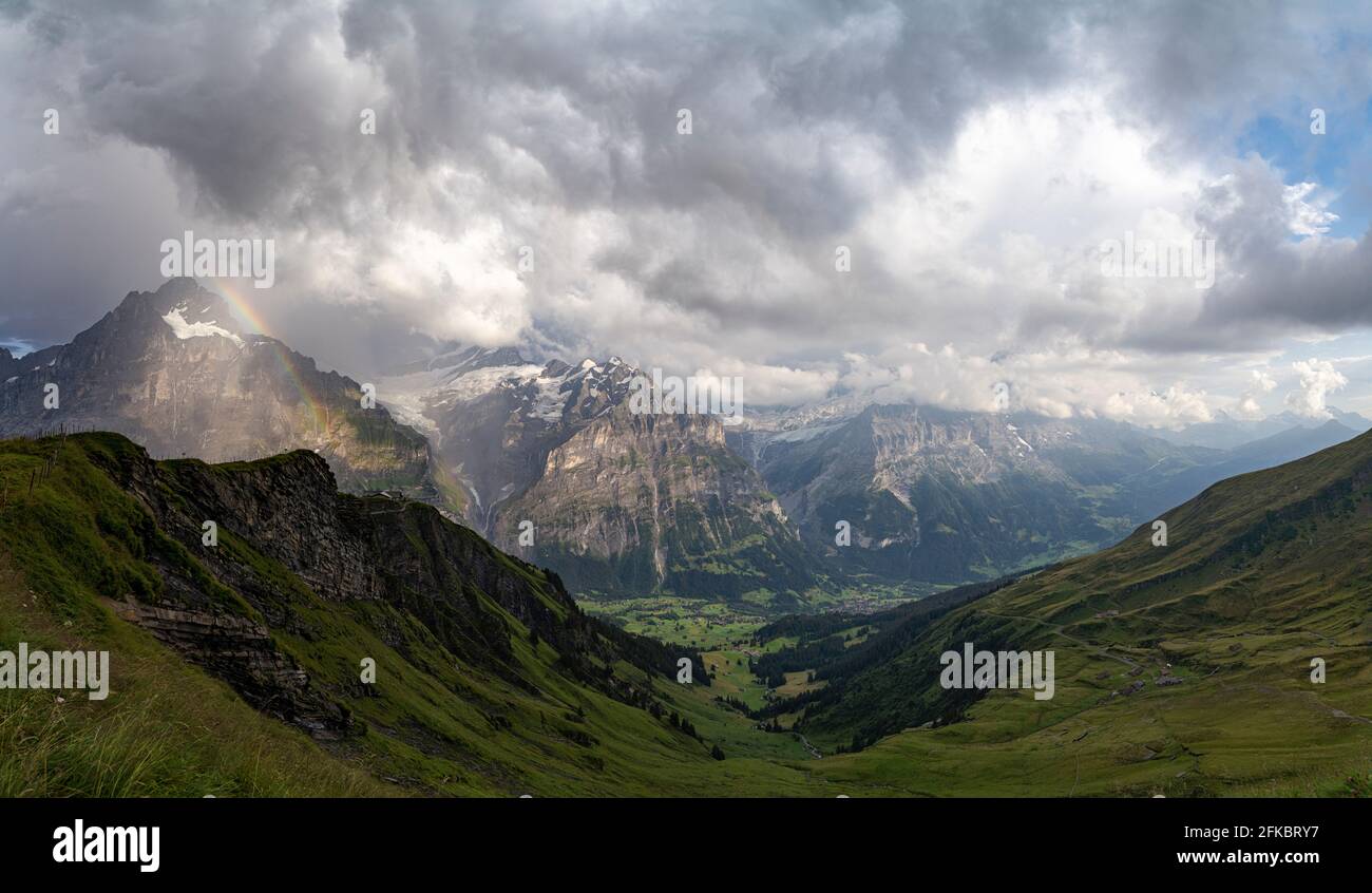 Panoramica della verde valle che circonda Grindelwald e Alpi Bernesi illuminate dall'arcobaleno, primo, Canton Berna, Svizzera, Europa Foto Stock