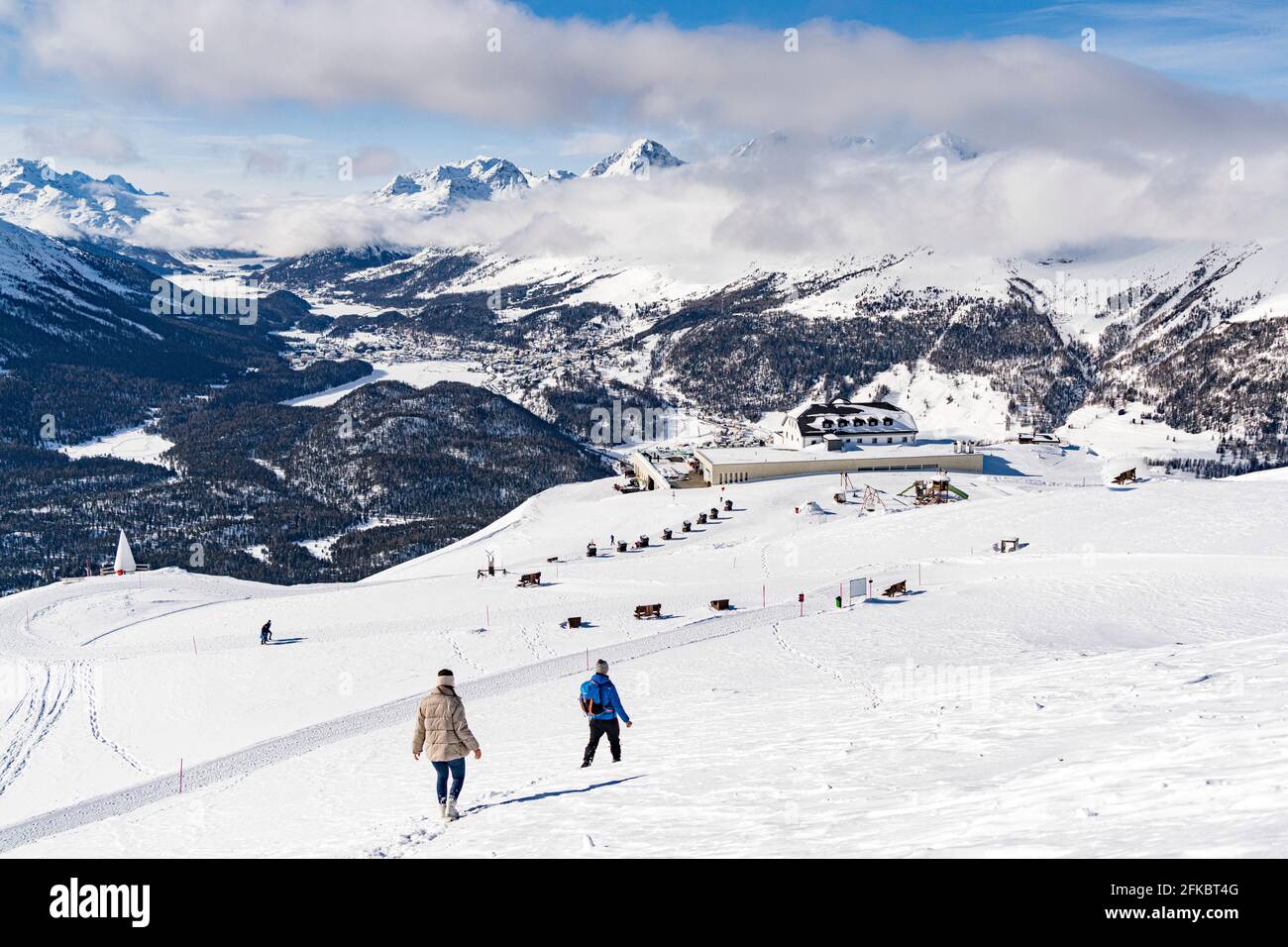 Due escursionisti che camminano su una pista innevata verso la stazione della funicolare di Muottas Muragl, Samedan, Engadina, Graubunden, Svizzera, Europa Foto Stock