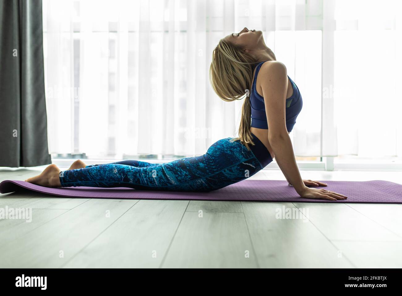 Yogi giovane donna che pratica yoga concetto, facendo King Cobra esercizio, Raja bhudjangasana posa, lavorando fuori indossando nero sportswear, tutta lunghezza silhou Foto Stock