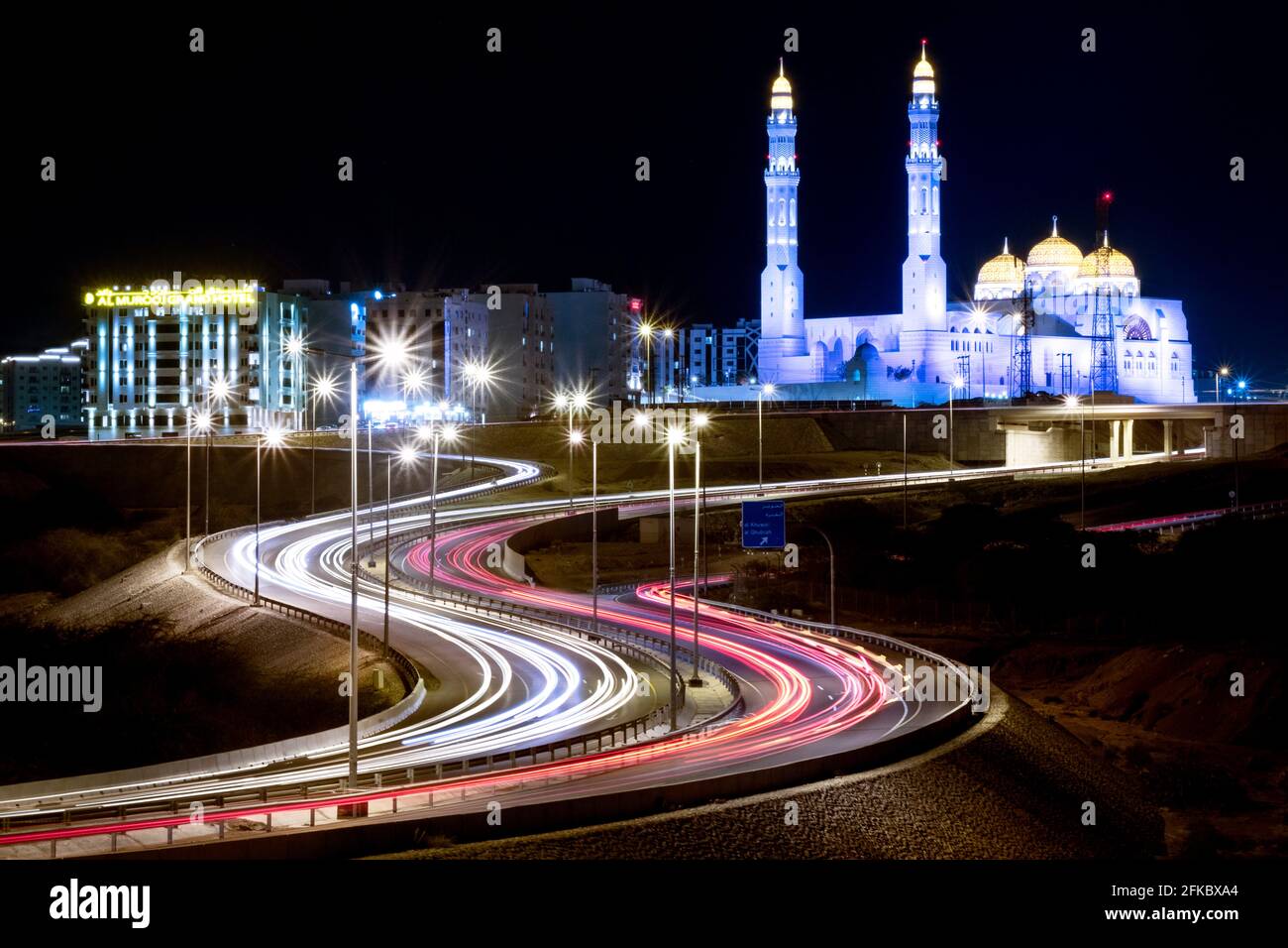 Lunga esposizione città notte ripresa con una moschea blu e una strada con percorsi in auto, Mascate, Oman, Medio Oriente Foto Stock
