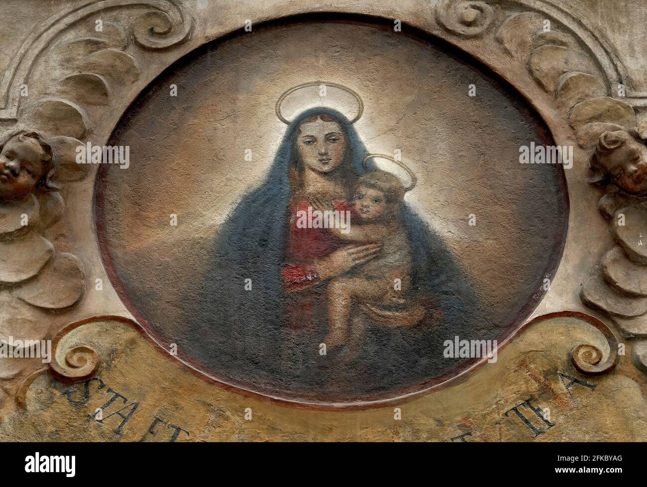 Questo dipinto ovale Madonna col Bambino adorna la facciata barocca della Casa di nostra Signora del Succore, una proprietà tardo-rinascimentale a Nerodova 36/211 a Malá Strana, la Città minore o il quartiere piccolo di Praga, capitale della Repubblica Ceca. Un nome precedente, alla Madonna Nera, deriva probabilmente da una leggenda che una statua della Madonna Nera di un villaggio vicino a Praga era qui nascosta in una cantina medievale contenente una sala di preghiera segreta. La casa è tra almeno 300 proprietà storiche a Praga per mostrare ancora segni casa tradizionale o targhe di nome. Foto Stock