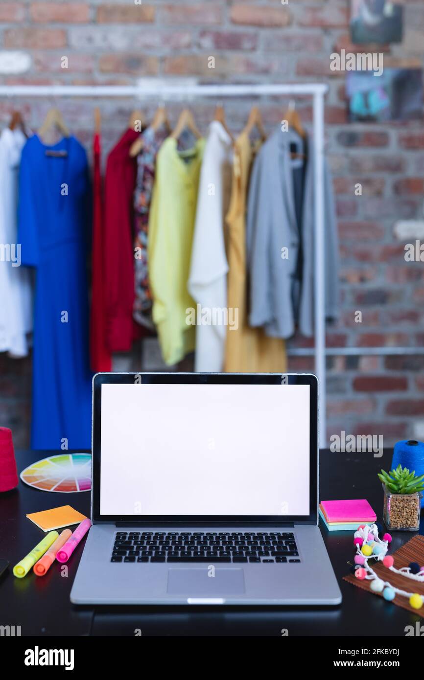 Computer portatile con spazio per la copia sullo schermo su una scrivania piena di accessori di designer Foto Stock