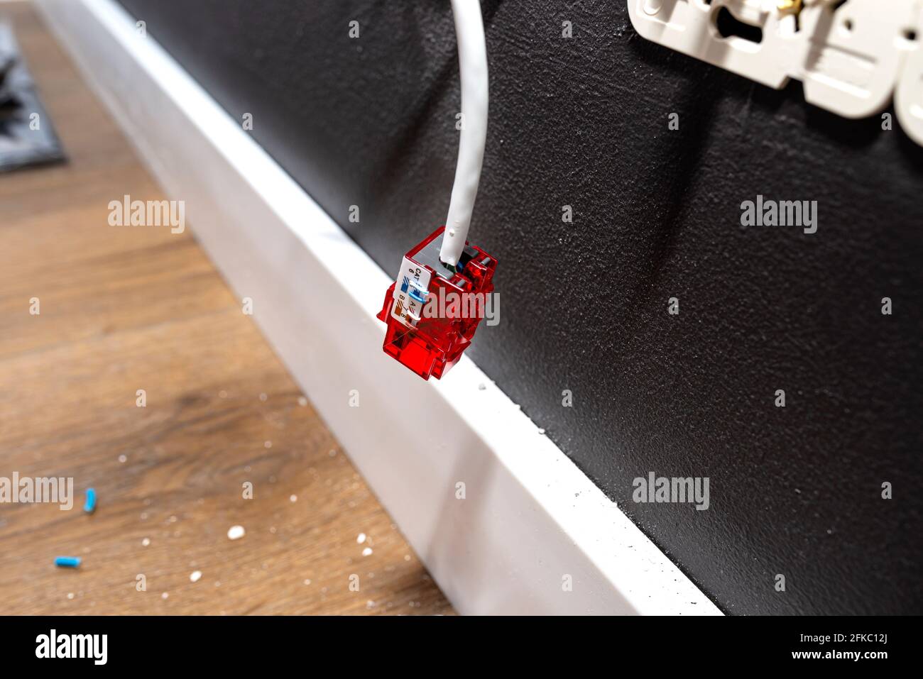 Un cavo di rete che sporge dalla parete con un modulo RJ45 pronto alla presa del computer nella stanza. Foto Stock