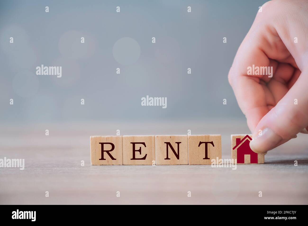 Investimento immobiliare e mutuo casa di concetto finanziario. Mano che tiene blocchi di cubetti di legno con l'icona della casa e AFFITTO parola. Investimenti immobiliari e casa Foto Stock