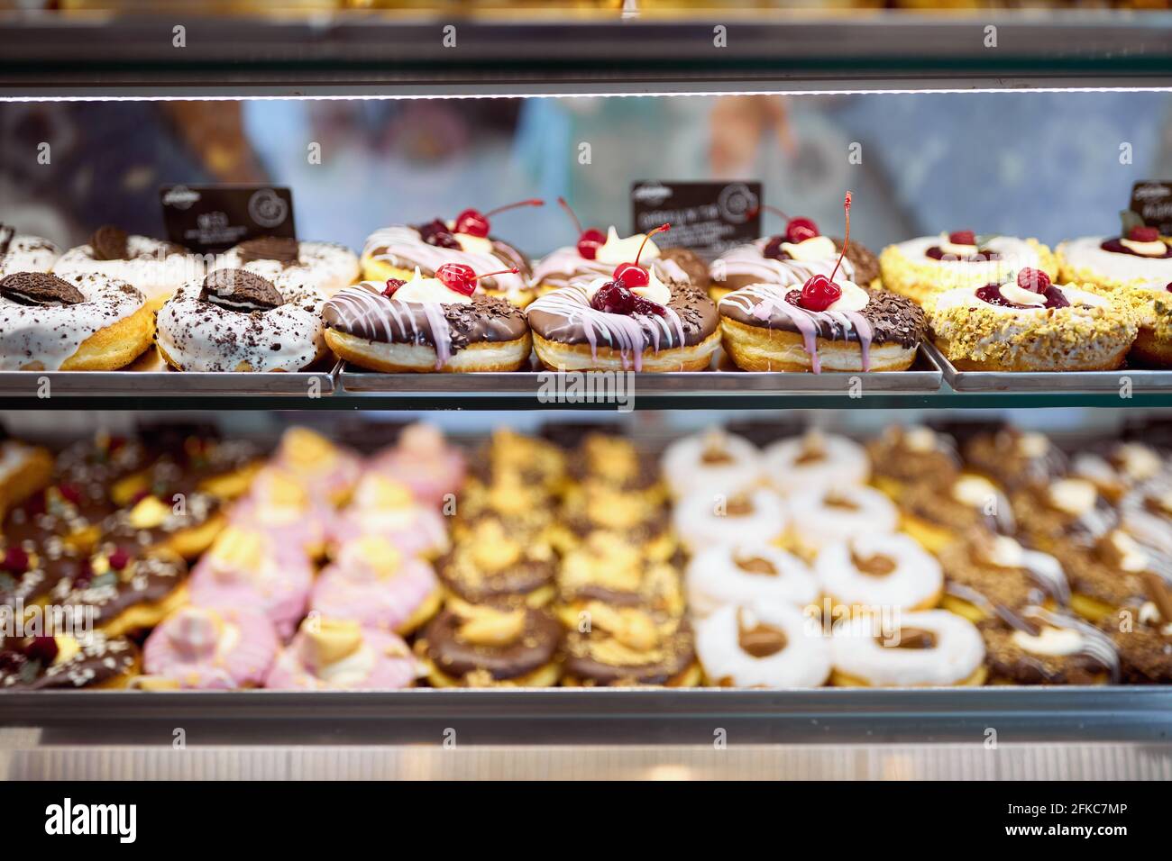 Una vetrina piena di deliziose ciambelle dall'aspetto irresistibile in un negozio di caramelle. Pasticceria, dessert, dolce Foto Stock