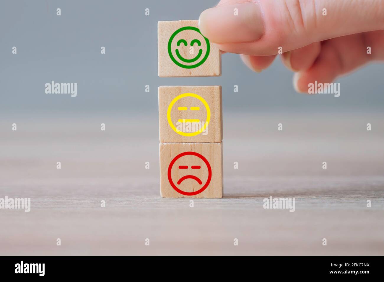 Esperienza di assistenza clienti e sondaggio sulla soddisfazione aziendale. Mano che prende la scelta del cubo del blocco di legno con l'emozione del sorriso del viso. Revisione positiva del cliente Foto Stock