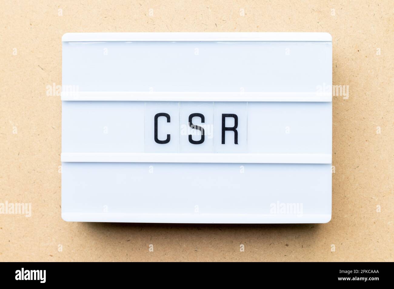Scatola luminosa bianca con la parola CSR (abbreviazione della responsabilità sociale d'impresa) su sfondo di legno Foto Stock
