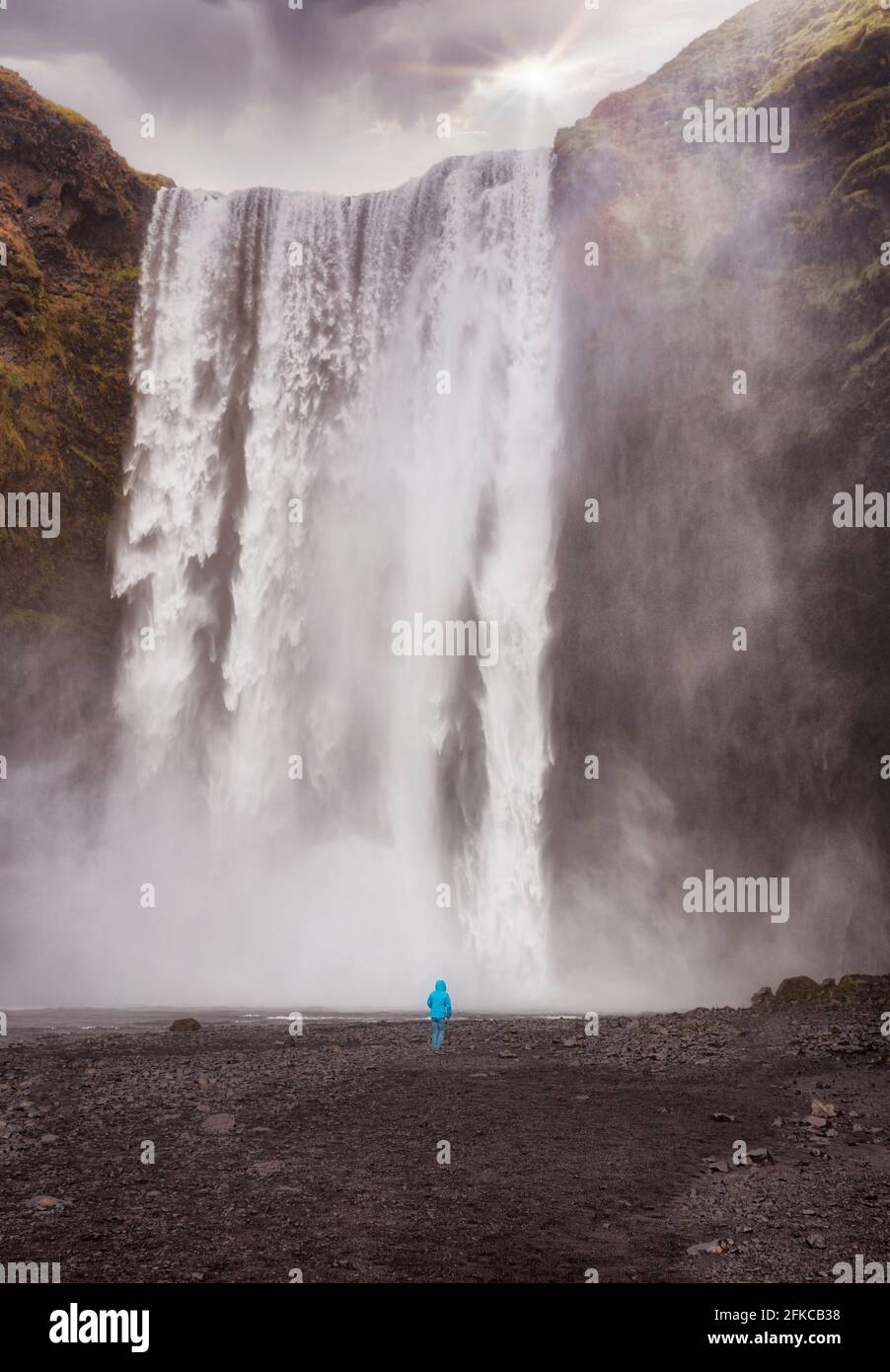 Un bambino si trova di fronte alla cascata Skogafoss in islanda Foto Stock