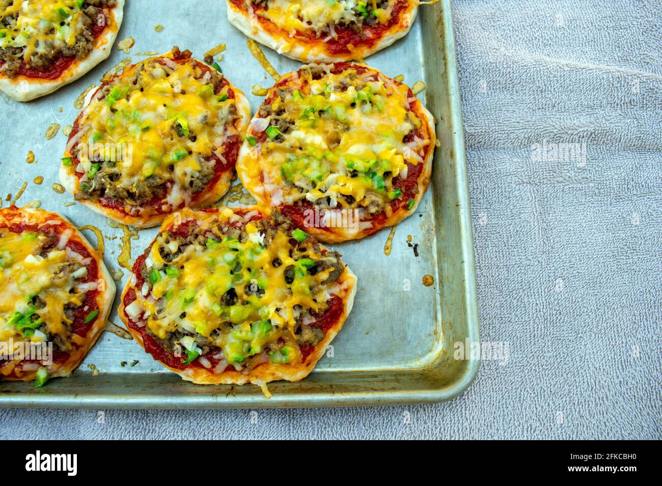 Il formaggio è perfettamente fuso su questa piccola pizze fatte in casa in miniatura che sono appena uscito dal forno. Foto Stock