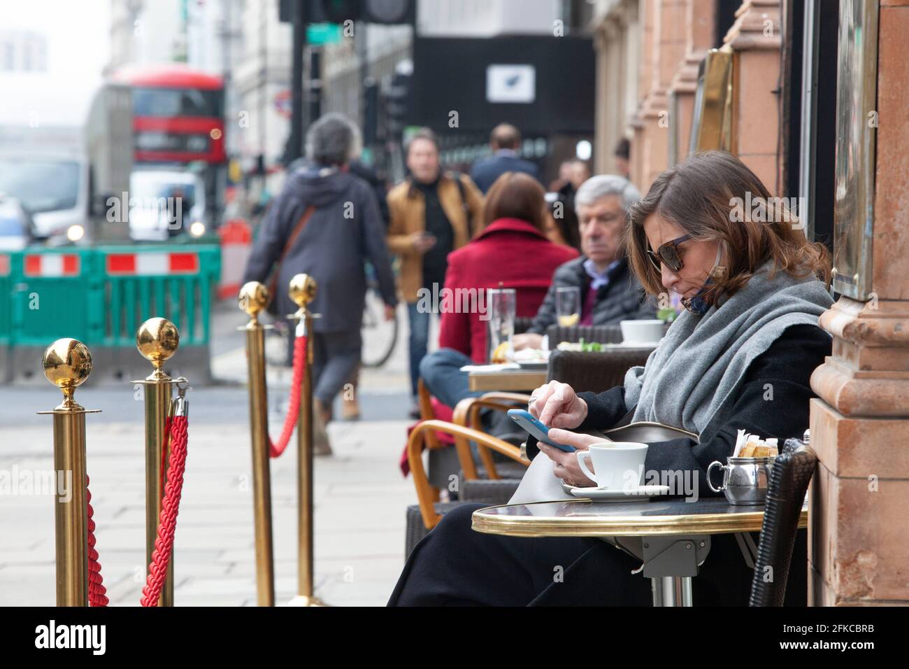 Londra, Regno Unito. 30 aprile 2021. Nonostante il tempo più fresco del solito e il traffico intenso che passa, le persone si siedono all'esterno dei caffè di Piccadilly, in quanto la cena al coperto non sarà consentita fino al 17 maggio. Credit: Anna Watson/Alamy Live News Foto Stock