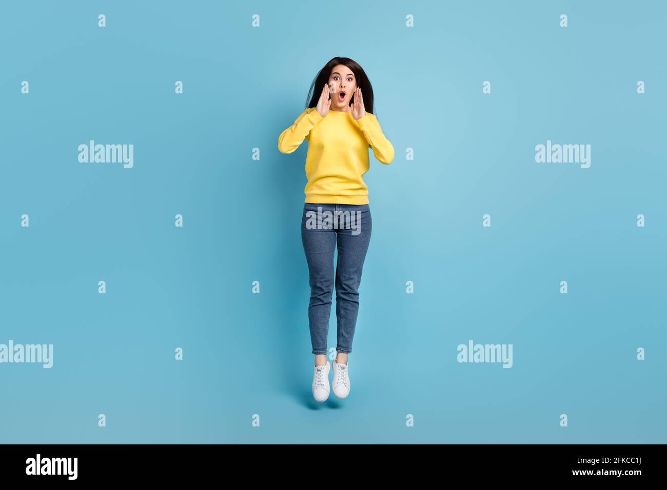 Foto di scioccato presentatore signora salto palme bocca aperta grido indossare scarpe gialle jumper jeans isolato sfondo blu Foto Stock