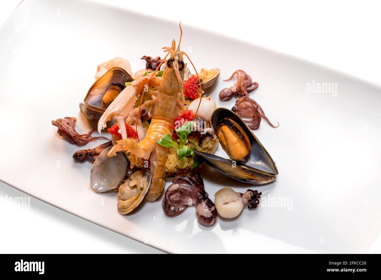 Frutti di mare e crostacei con cous cous, piatto colorato con scampi, cozze, vongole, polpo bambino e caviale rosso Foto Stock