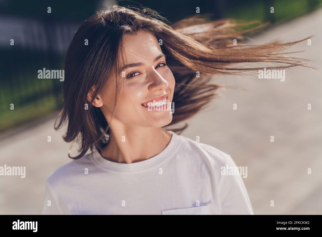 Foto di ottimista bruna signora aria soffio indossare panno bianco passeggiate nel parco esterno Foto Stock