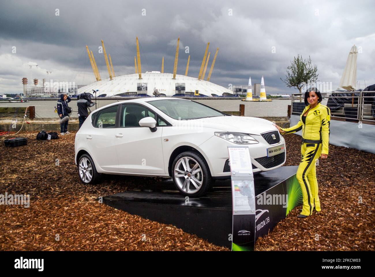 Modello femminile che promuove le vetture Seat alla Red Bull Air Race di Londra 2008. Ragazza IN SELLA Auto sponsorizzato vestito giallo. Cielo scuro e pesante sull'arena O2 Foto Stock