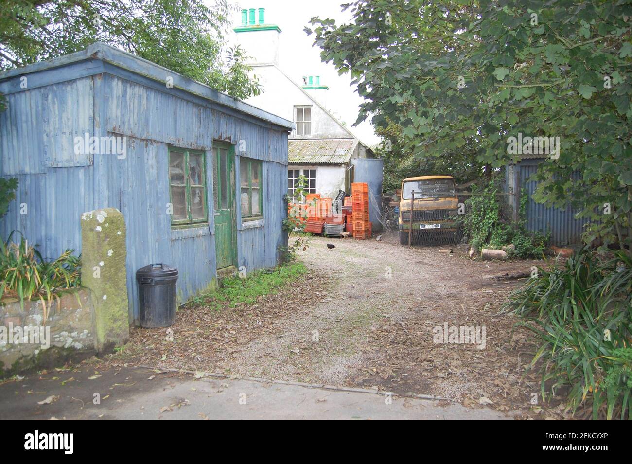 Fienile in azienda agricola Jersey Farm Farmers ha cestino in metallo fabbricato serbatoio di gas vialetto di passaggio furgone ingresso in ghiaia vecchio stile vialetto di passaggio in calcestruzzo Foto Stock