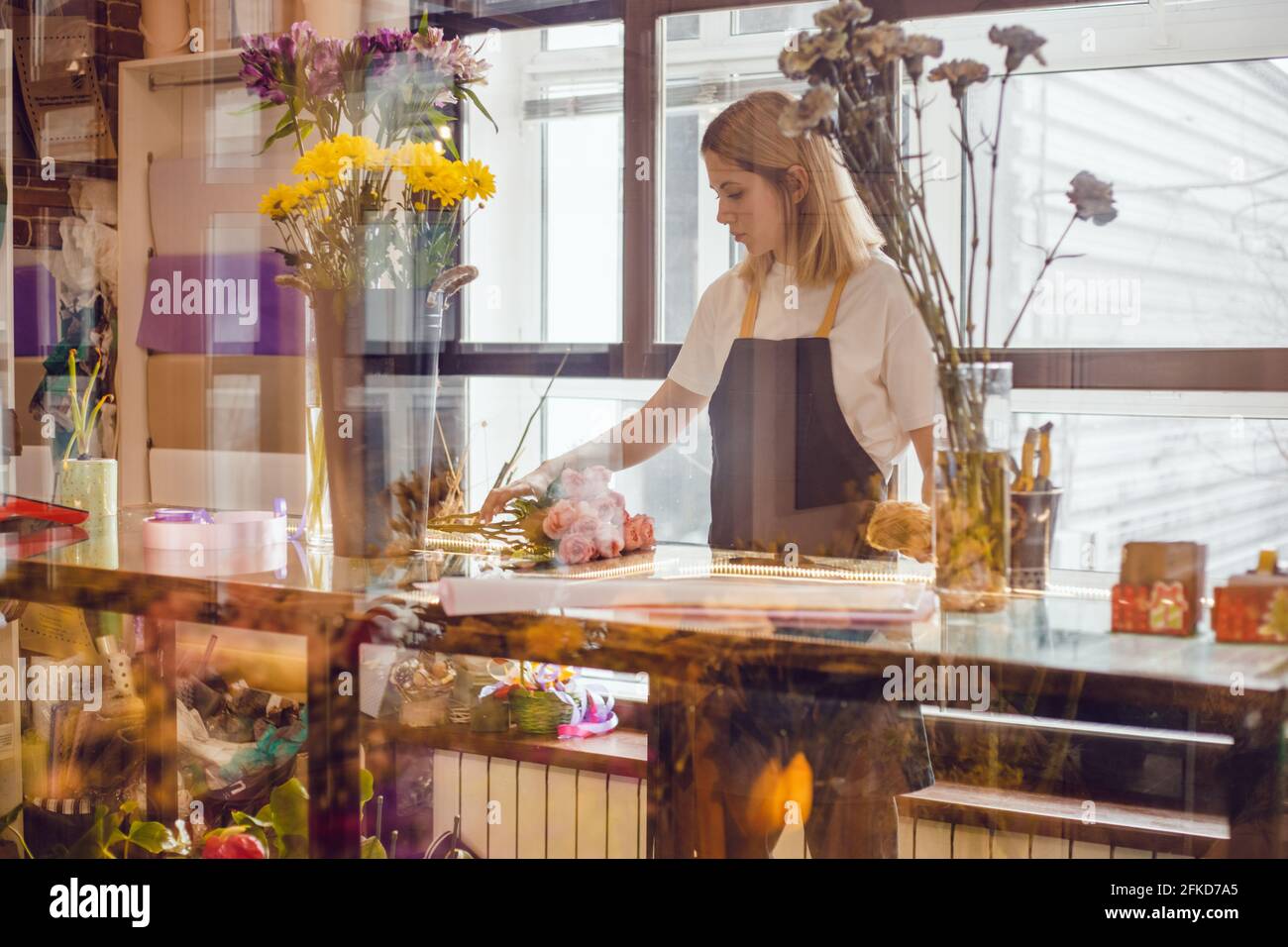 Fiorista ragazza raccoglie una composizione di fiori in un negozio di fiori. Foto Stock