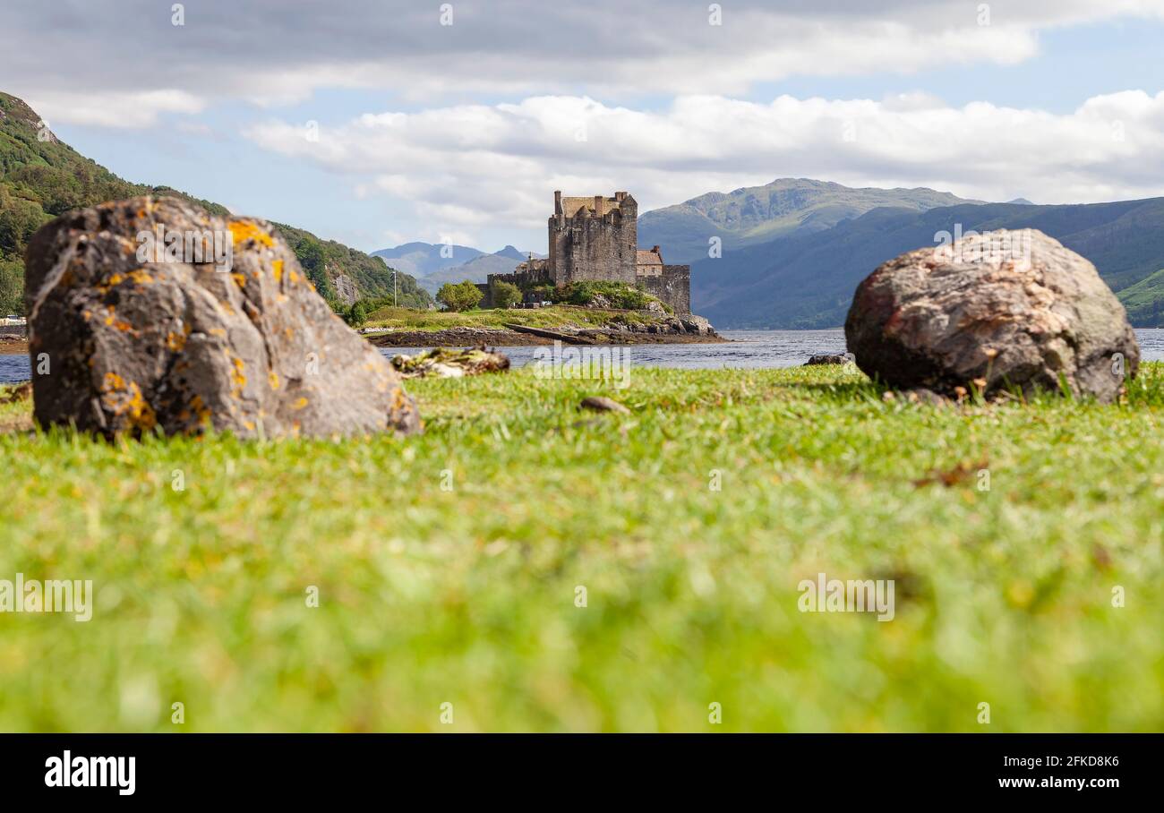 Un castello sulla cima di un campo erboso coperto con Eilean Donan sullo sfondo Foto Stock
