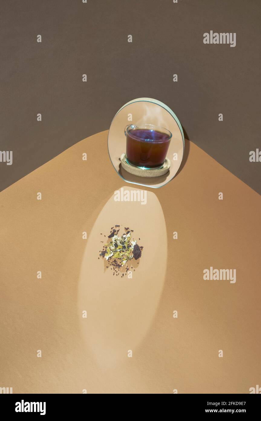 Illusione ottica della tazza calda di tè e gli ingredienti riflettono nello specchio. Due morbidi colori di tendenza sfondo. Concetto minimo di bevande calde. Foto Stock