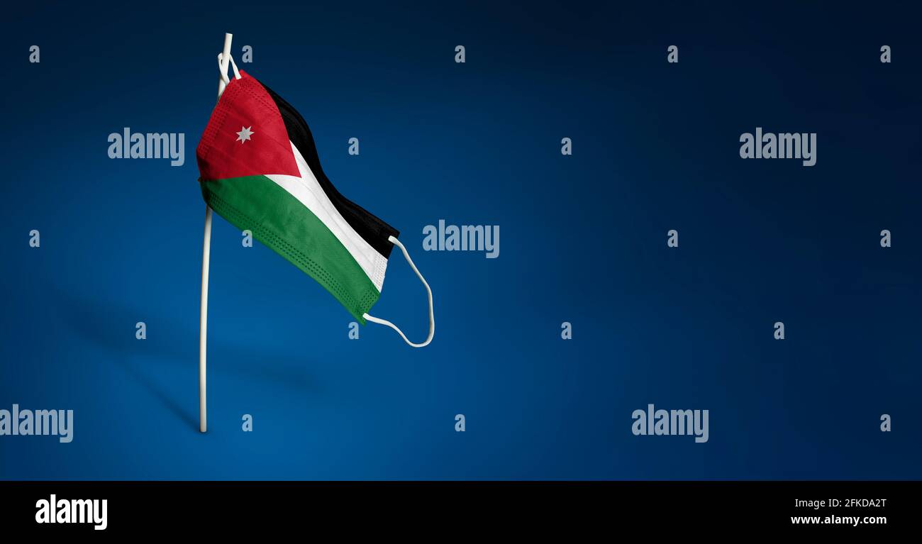 Maschera di Giordania su sfondo blu scuro. Bandiera ondulata di Giordania dipinta su maschera medica sul palo. Concetto del banner della lotta contro l'epidemia Foto Stock