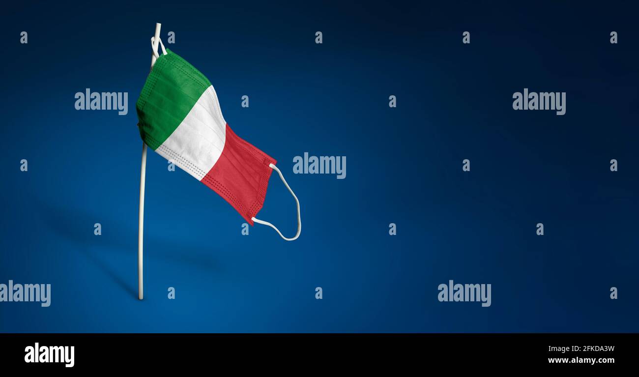 Maschera Italia su sfondo blu scuro. Bandiera ondulata d'Italia dipinta su maschera medica sul palo. Concetto del banner della lotta contro l'epidemia Foto Stock