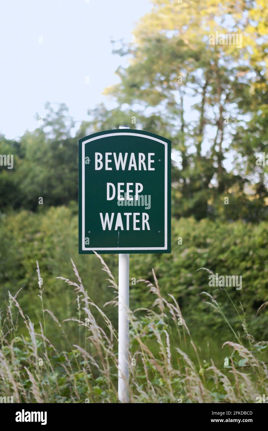 Fate attenzione al segnale dell'acqua profonda accanto ad un laghetto di bilanciamento (stagno di ritenzione) sul Pix Brook, Fairfield, Bedfordshire, Regno Unito Foto Stock