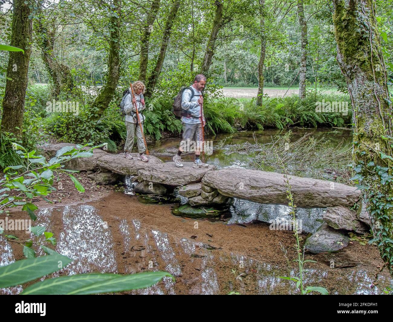 Saltando su massi a ponte de Penas sul Camino a Santiago de Compostela, Melide, Spagna, 23 luglio 2010 Foto Stock