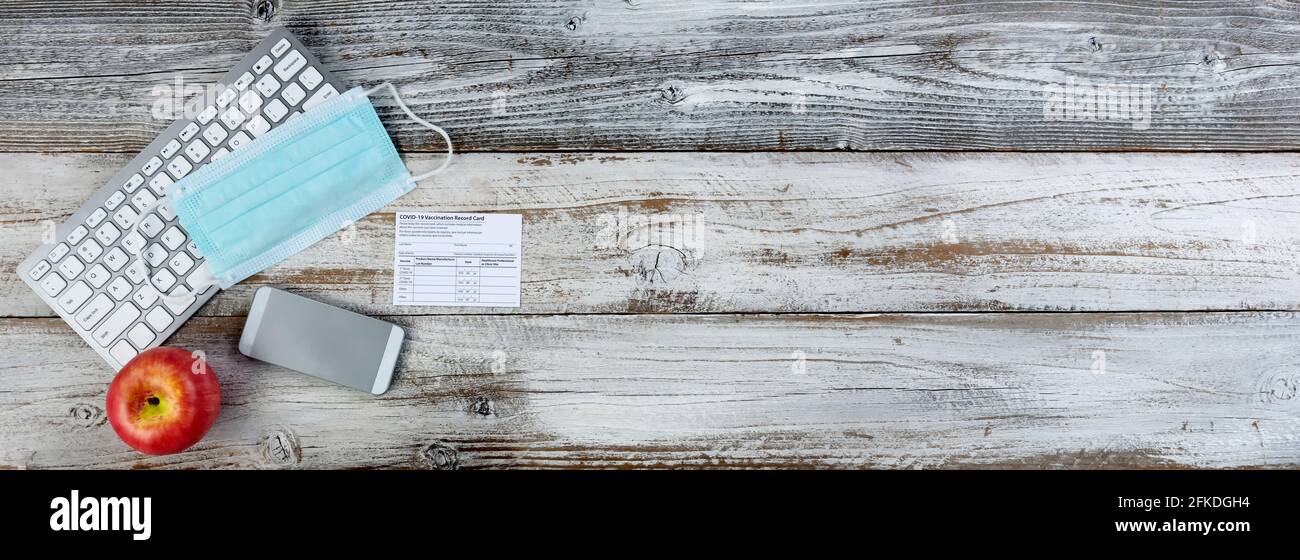 Covid 19 scheda di registrazione delle vaccinazioni per tornare a scuola o in ambiente di lavoro su desktop di legno bianco. Record individuale da utilizzare durante il c Foto Stock