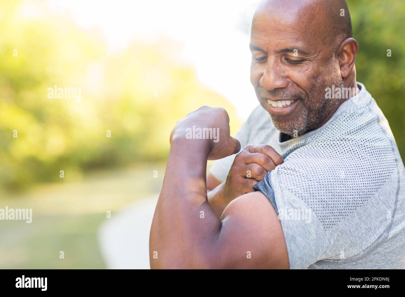 Matura afroamericana che flette il suo muscolo bicep. Foto Stock