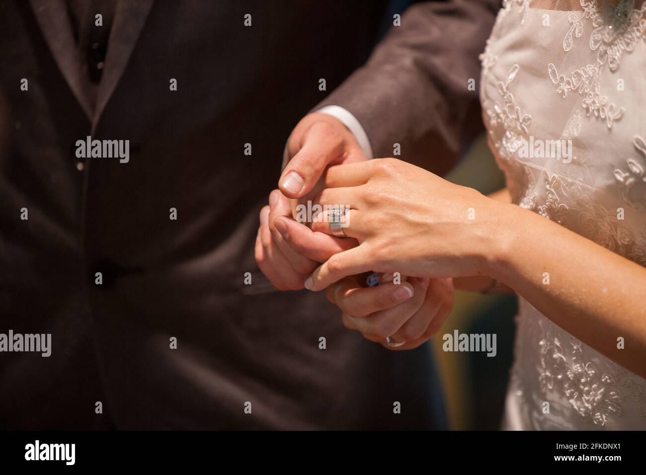 Primo piano di sposa che mette un anello di nozze sul dito dello sposo. Coppie che si scambiano gli anelli di nozze. Foto di alta qualità Foto Stock