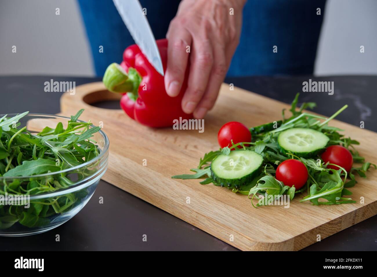 Sezione centrale della donna che prepara l'insalata sul tagliere di legno Foto Stock