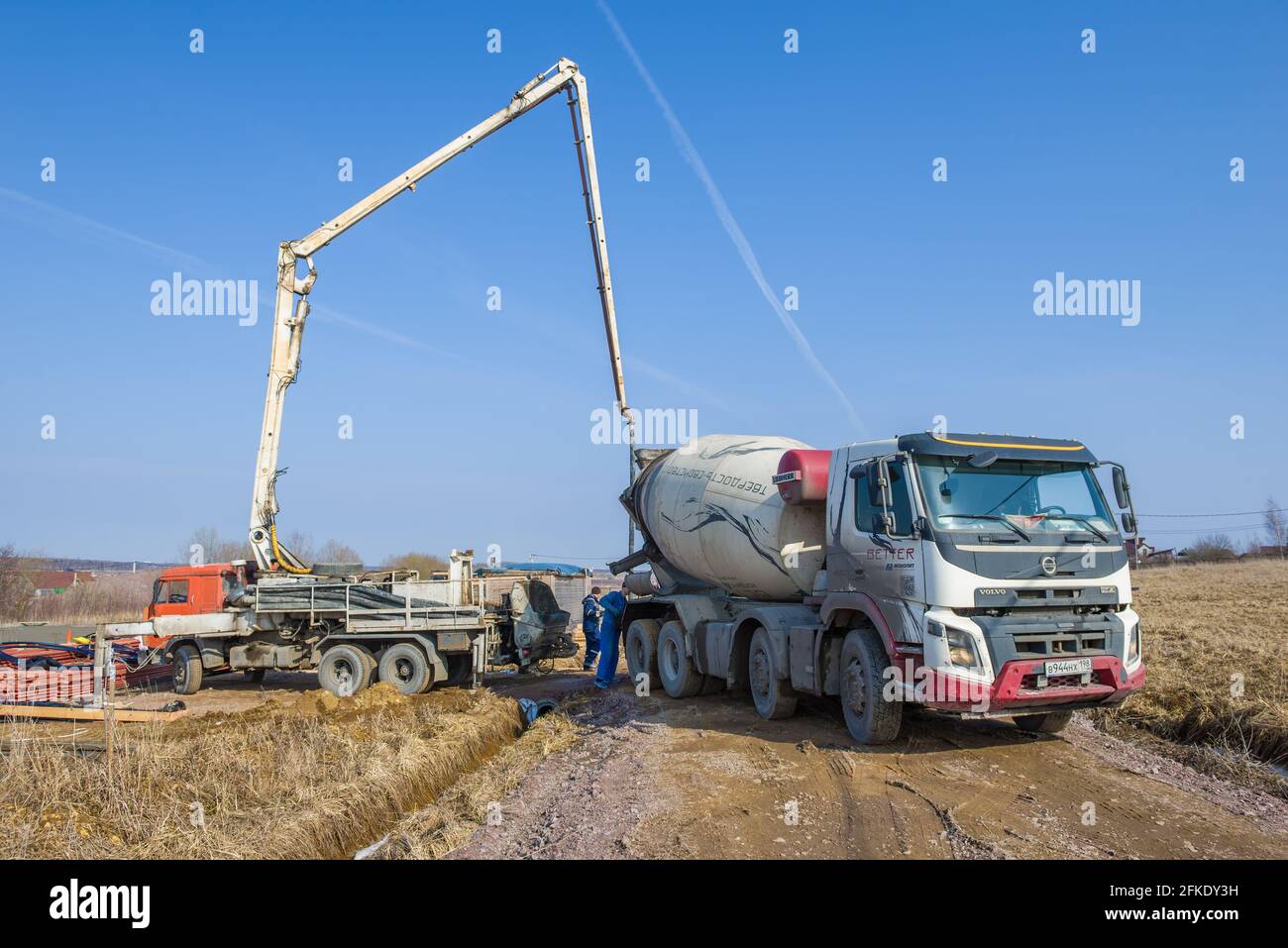 LENINGRADO REGIONE, RUSSIA - 28 MARZO 2021: Un camion betoniera e una pompa di calcestruzzo sulla costruzione di una casa di campagna in un giorno di marcia soleggiato Foto Stock