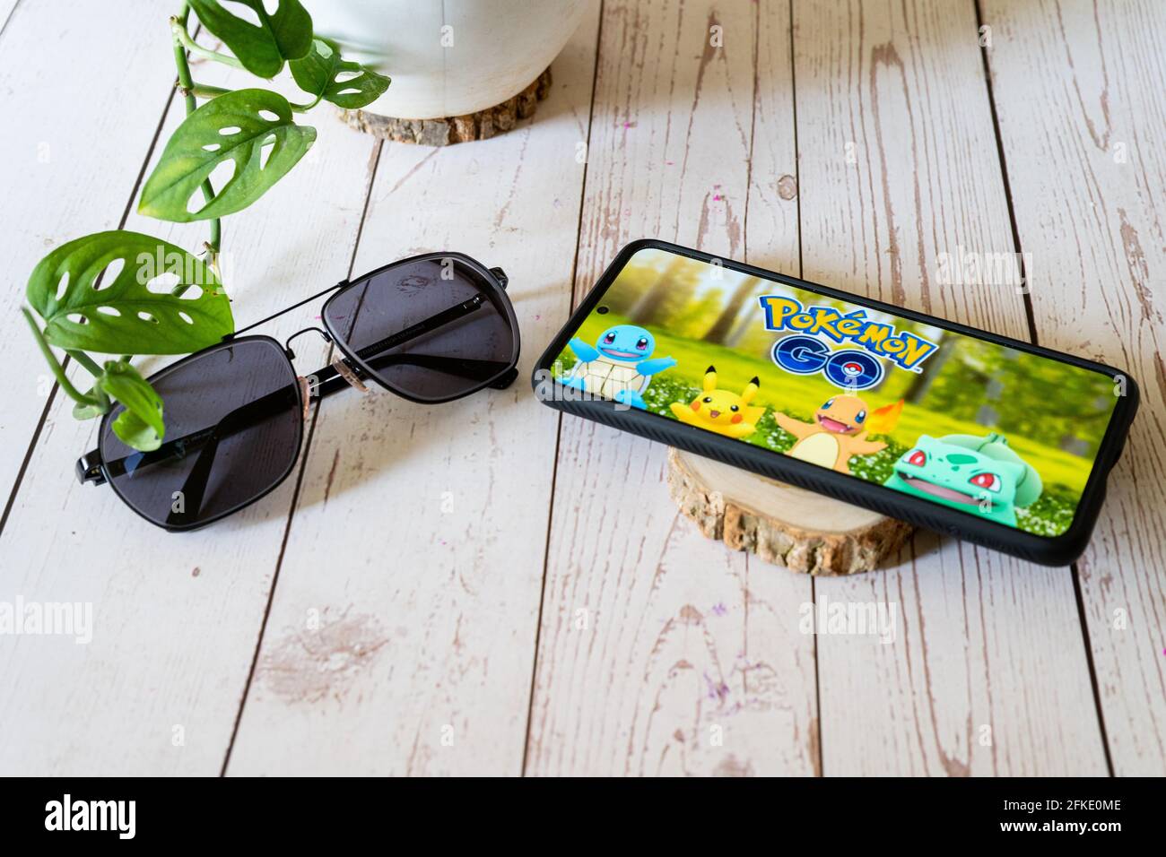 famoso gioco virtuale di realtà aumentata pokemon go che gioca su uno  telefono cellulare su un tavolo di legno all'aperto con occhiali di  protezione per piante mostrare alle persone che apprezzano questo