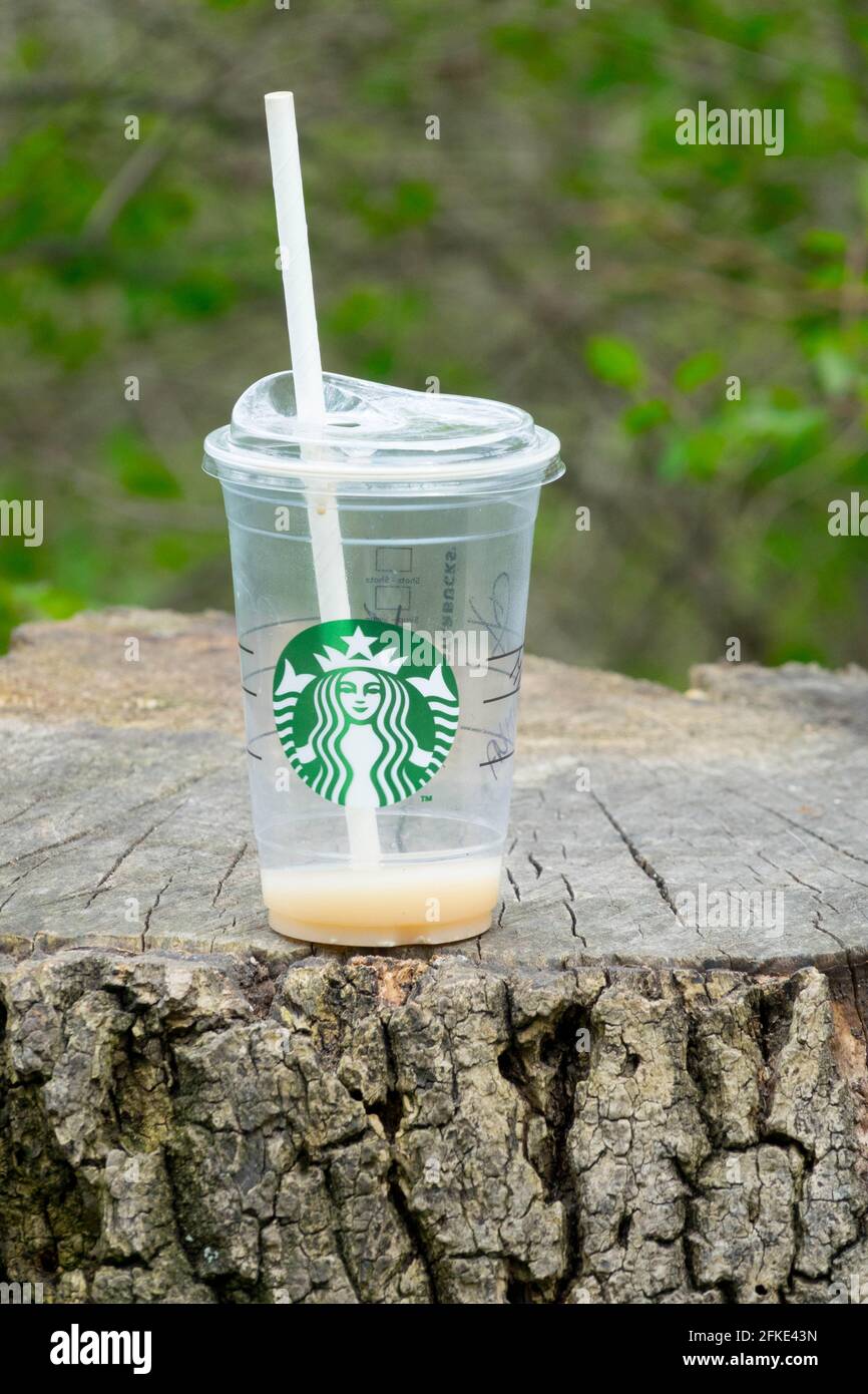 Svuotare la tazza di caffè Starbucks con una cannuccia su un moncone Foto Stock